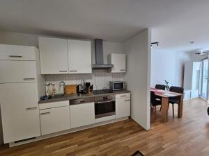 因斯布鲁克Stylish Apartment in Innsbruck + 1 parking spot的厨房配有白色橱柜、桌子和用餐室。