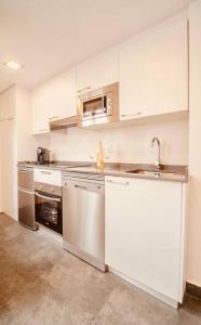 格拉纳达Torre de la Vela 1的厨房配有白色橱柜和不锈钢用具