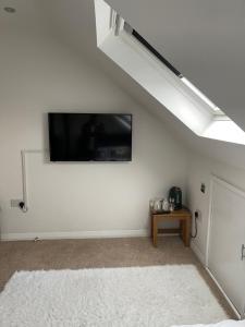 BroadwaterNISHAT & AMAAN的客厅配有白色墙壁上的平面电视。
