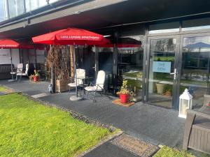 亚历山德里亚loch lomond apartments的一间带桌椅和红伞的餐厅