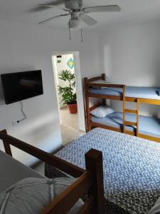 瓜鲁雅Pousada Sol da Manhã的客房设有带一张床和电视的卧室。