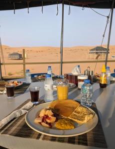 Al WāşilHamood desert local camp的一张桌子,上面有一盘早餐食品和饮料