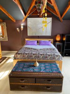 PaulTienne Del Mar的一间卧室配有一张带紫色枕头的床和木制天花板