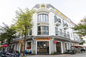 朔庄Nét Việt Hotel Vincom Sóc Trăng的一座白色的建筑,前面停有摩托车