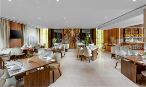 麦地那فندق جايدن-Jayden Hotel的配有木桌和白色椅子的餐厅