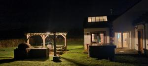 巴洛赫Auchendennan Farm Self Catering Cottages的夜间带凉亭和房子的后院