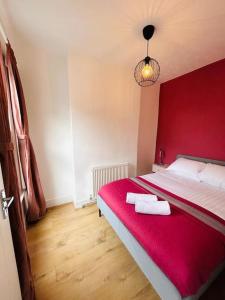 伦敦Elegant House in Stratford的一间卧室配有红色的床和2条毛巾