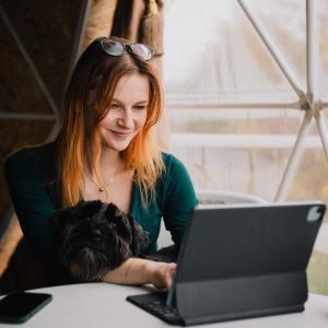 Готель Еко Сфера的带着狗的女人看着笔记本电脑