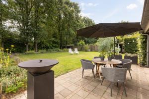 米尔洛Onder het dak van Brabant的庭院配有桌椅和遮阳伞。