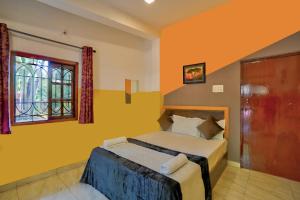 卡兰古特Calangute By Goa Journey的一间卧室设有一张黄色墙壁和窗户的床