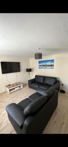 利物浦Entire 3 bedrooom holiday home的客厅配有黑色沙发和平面电视。