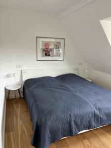提努姆Schaumis Hus的白色卧室配有蓝色的床和一张桌子