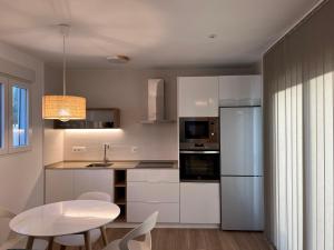 加的斯Loft luxury Mirador的厨房配有白色橱柜、桌子和白色冰箱。