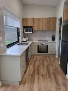 麦夸里港Coastal Pod的厨房铺有木地板,配有白色的柜台和水槽。