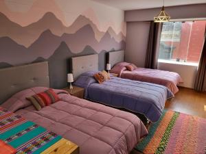 利马Espaciosos y lindos mini apartamentos的墙上漆有山脉的房间里设有三张床