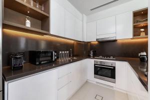 迪拜Luxurious 2BR apt with panoramic Marina view的白色的厨房配有白色橱柜和电器