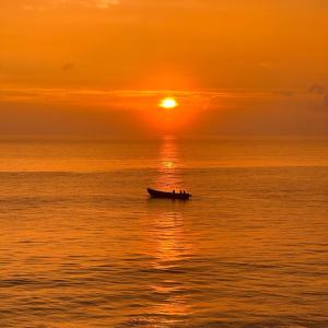 瓦尔卡拉Maadathil Cottages & Beach Resort的日落时分在海洋中的船只