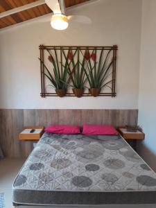 卡拉瓜塔图巴Recanto da Praia Kitnetes的卧室配有一张挂在墙上的植物床
