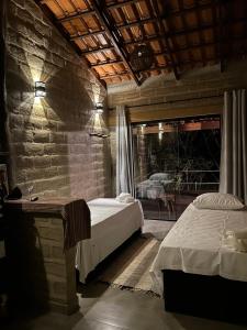 圣若热岛Chalé Pousada Maná do Céu - São Jorge的一间卧室设有两张床和石墙