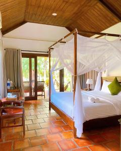 富国槟城侨海滩度假酒店的一间卧室,卧室内配有一张天蓬床