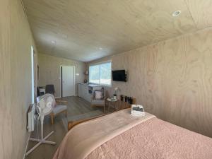 KumeuCotman Cottage on Coatesville的一间卧室配有一张床,另一间配有电视。