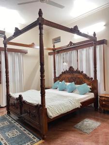 哈桑Amayaa Courtyard Homestay的一间卧室配有一张带蓝色枕头的木制天蓬床