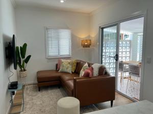 BrightonModern Pool Oasis & Seaside Abode的一间带棕色沙发的客厅和一个阳台