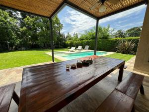 Del VisoDivina casa con parque pileta en mini barrio cerrado.的后院的木桌,带游泳池