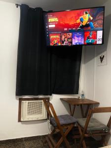 阿拉亚尔-杜卡布Suíte Trilha do Sol 2的挂在墙上的电视,配有桌椅