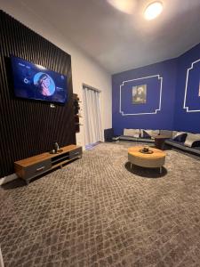 开罗downtown Family Suites的一间大客厅,客厅里设有大屏幕电视,墙上是蓝色的墙壁
