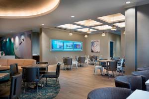 新士麦那海滩SpringHill Suites by Marriott New Smyrna Beach的一间设有桌椅和电视的等候室