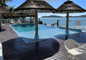 邦比尼亚斯Bombinhas Tourist Apart的木制甲板上带遮阳伞的游泳池