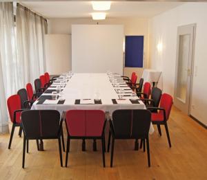 诺斯罗驰菲尔德伯克餐厅酒店的一间会议室,配有长桌子和红色椅子