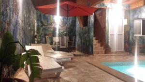 米勒福特Mirleft Tayought Guest House的一个带游泳池和红伞的房间