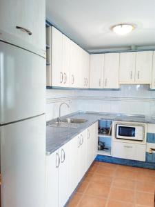 马贝拉Apartamento las terrazas的厨房配有白色橱柜和不锈钢冰箱