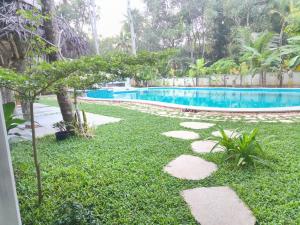 马拉利库兰Marari Beach Bungalow的一个带游泳池、草地和岩石的庭院