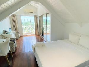 BelmontBay House Grenada的卧室设有一张白色大床和一扇窗户。
