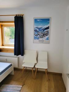 达沃斯Ferienwohnung Parsenn Peaks Panorama的一间卧室配有两把白色椅子和窗户