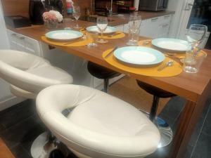 韦尼雪Le Petit Cocon - Parking privé - Lyon Sud的一张桌子、两把白色椅子和一张木桌板