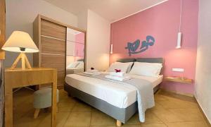 帕琉乔拉Art Apartment的一间卧室配有一张带书桌的床和粉红色的墙壁