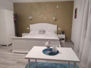 巴亚马雷Casa cu trandafiri的卧室配有白色的床和带蜡烛的桌子。