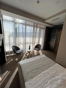 第比利斯Hotel Sky Station的一间卧室配有两把椅子和一张床,设有窗户。