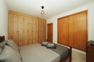 阿玛考德佩拉Apartamento Cristina - Próximo da praia的一间卧室配有一张床和木制橱柜