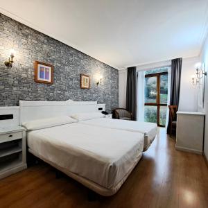 坎加斯-德奥尼斯坎加斯奥尼斯城酒店的一间卧室设有两张床和砖墙