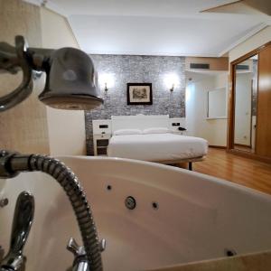 坎加斯-德奥尼斯坎加斯奥尼斯城酒店的带浴缸的浴室和带两张床的客房。