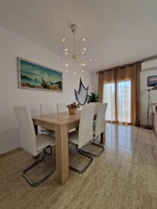 坎布里尔斯Beach Apartment Regueral的一间带木桌和白色椅子的用餐室
