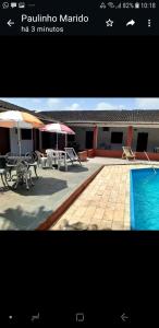 卡纳内亚Pousada Por do Sol的一张带游泳池、桌子和遮阳伞的庭院的照片