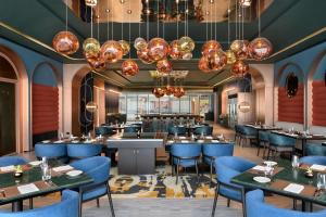 科钦The Artiste Kochi, a Tribute Portfolio Hotel的餐厅设有蓝色的桌椅和吊灯。