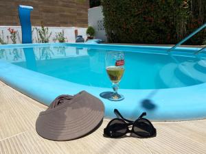 帕里普埃拉Casa Paraiso de Sonho Verde的游泳池旁的帽子和太阳镜以及一杯葡萄酒