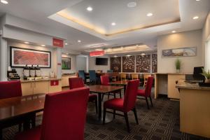 休斯顿休斯顿威斯切斯万豪广场套房酒店的用餐室配有桌子和红色椅子